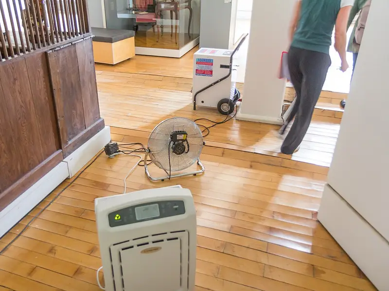 Secado con ventiladores de un suelo de madera dañado por agua