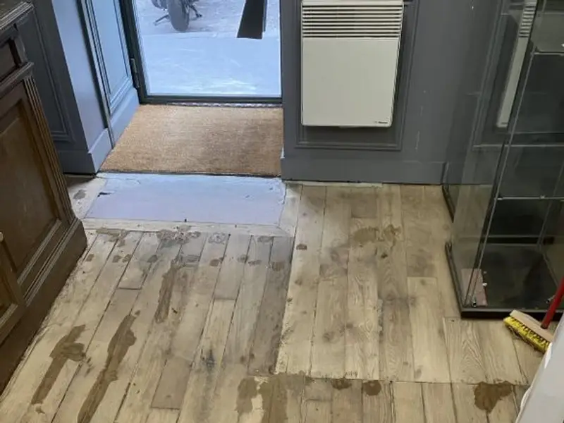 Suelo de madera con manchas y zonas dañadas antes de su reparación