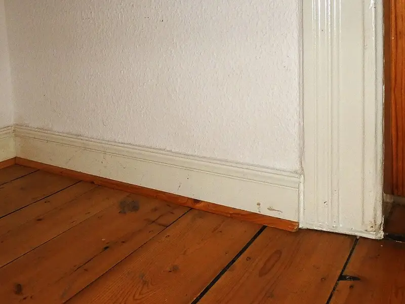 Suelo antiguo de tablas de pino con rodapié de madera